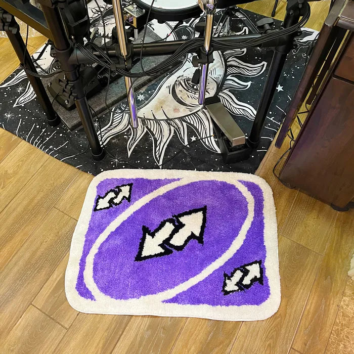 VibeCore UNO Reverse Accent Rug placed in front of a side table, featuring its playful purple design with a nostalgic UNO theme. This vibrant rug adds character and fun to any living room or bedroom, enhancing the space with its soft texture and quirky charm.