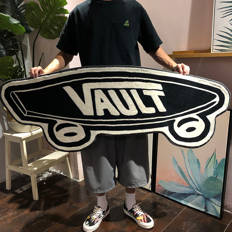 VibeCore Vans Vault Skateboard Accent Rug held up to display its bold, skateboard-inspired design with a black and white color scheme. This cute rug, featuring the iconic Vans Vault logo, adds a skate culture vibe to any room. Perfect for bedroom, dorm, or living room decor, it offers a playful, modern touch. The rug’s non-slip backing ensures safety and stability, making it an ideal small rug for tight spaces or as an accent piece. Bring street style into your home with this cool, aesthetic rug.