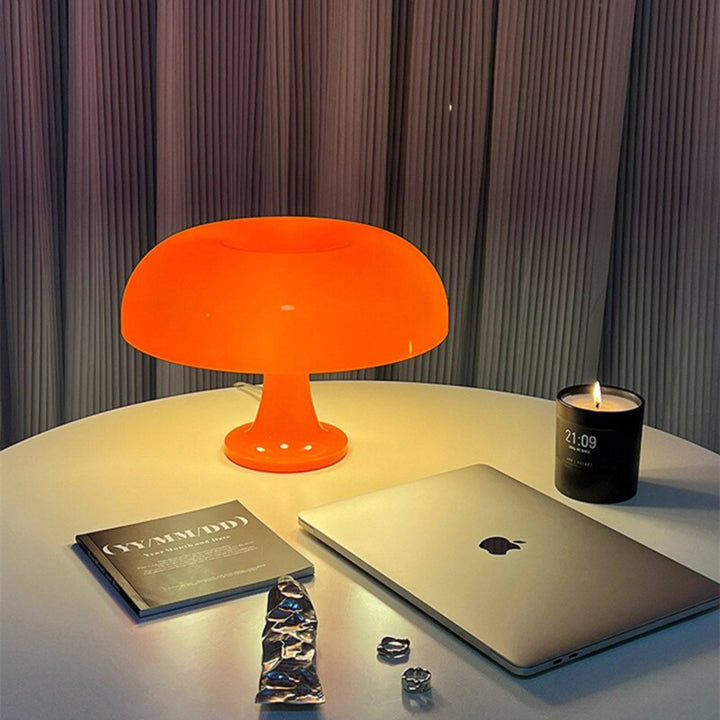 VibeCore Vintage 60s Mushroom Lamp in orange, lit up on a table, casting a soft, retro glow in a stylish room.