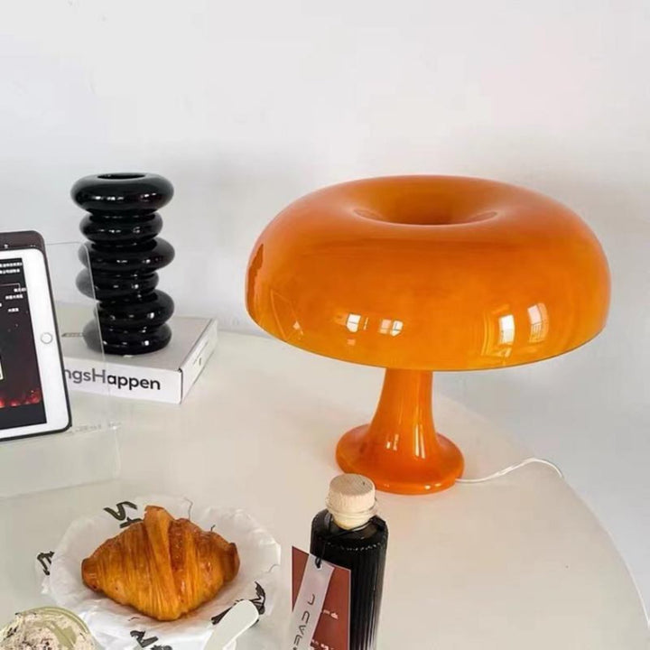 VibeCore Vintage 60s Mushroom Lamp in orange on a table, emitting a warm, retro glow in a cozy space.