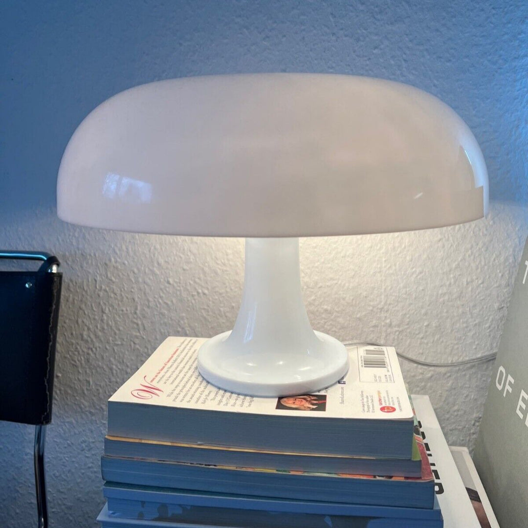 VibeCore Vintage 60s Mushroom Lamp in white, lit up, resting on a stack of books, creating a cozy and stylish ambiance.