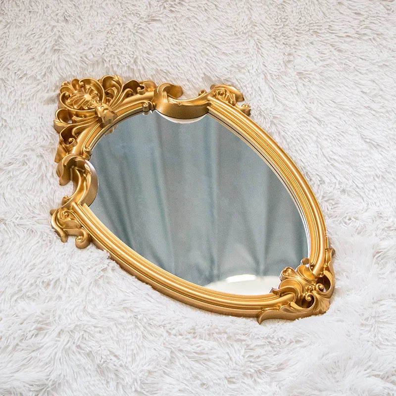 VibeCore Vintage Princess Coquette Mirror placed on a fluffy bedspread, showcasing its luxurious golden resin frame and European-inspired carved design, adding elegance and charm to the space.