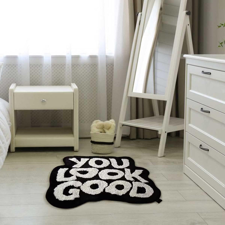 Aerial front view of the VibeCore You Look Good Accent Rug in black, showcasing its motivational quote design, soft plush texture, non-slip backing, and cute rug appeal. A modern, stylish rug that adds personality, comfort, and a playful touch to bedrooms, dorms, or living rooms. This aesthetic rug complements contemporary spaces with its chic design, offering a vibrant and uplifting accent for any room. Perfect for those looking to add a fun, cozy vibe to their home decor.