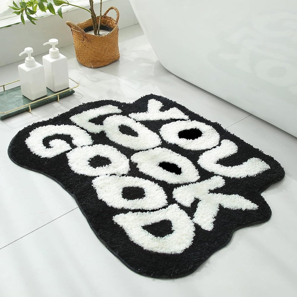 Close-up of the VibeCore You Look Good Accent Rug in black, highlighting its uplifting quote design, soft plush texture, non-slip backing, and cute rug appeal. This modern, cozy rug adds personality, comfort, and a stylish touch to bedrooms, dorms, or living rooms. Perfect for contemporary spaces, it offers a vibrant, motivational accent to brighten any room with its playful yet chic design. Ideal for anyone seeking a fun, aesthetic rug to complement their decor.