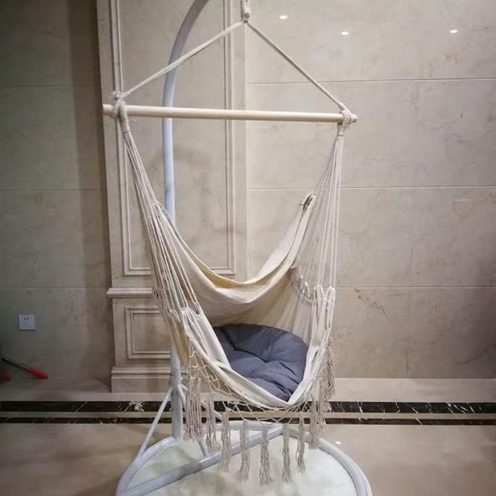 Aesthetic Bohemia style hanging hammock chair hanging in an apartment made of high-quality cotton thread perfect for adding a cozy, bohemian touch to your indoor space while providing durable comfort for lounging or reading.