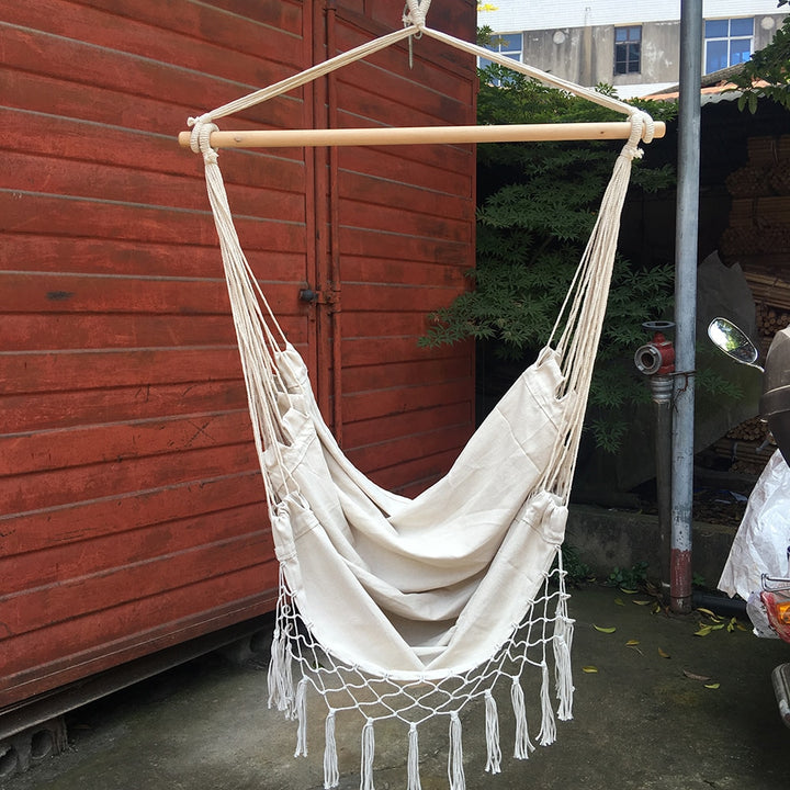 Aesthetic Bohemia style hanging hammock chair hanging outside made of high-quality cotton thread perfect for adding a cozy, bohemian touch to your outdoor space while providing durable comfort for lounging or reading.