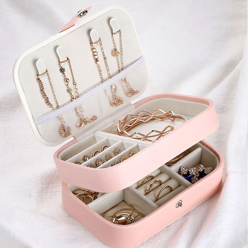 Compact jewelry organizer featuring two layers with compartments for rings, necklaces, and earrings. Soft velvet interior, durable synthetic leather exterior, perfect for travel or bedroom storage.