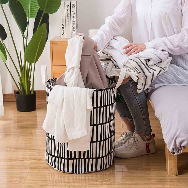 VibeCore Foldable Abstract Laundry Basket being used for laundry, showcasing its large-capacity, waterproof, and dustproof design with reinforced handles for easy transport.