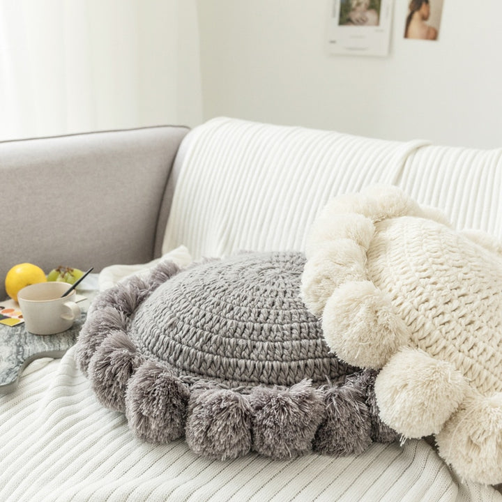 VibeCore Hand-Knitted Pompom Cushions in white and gray, stacked on a couch, showcasing their cozy, boho design.