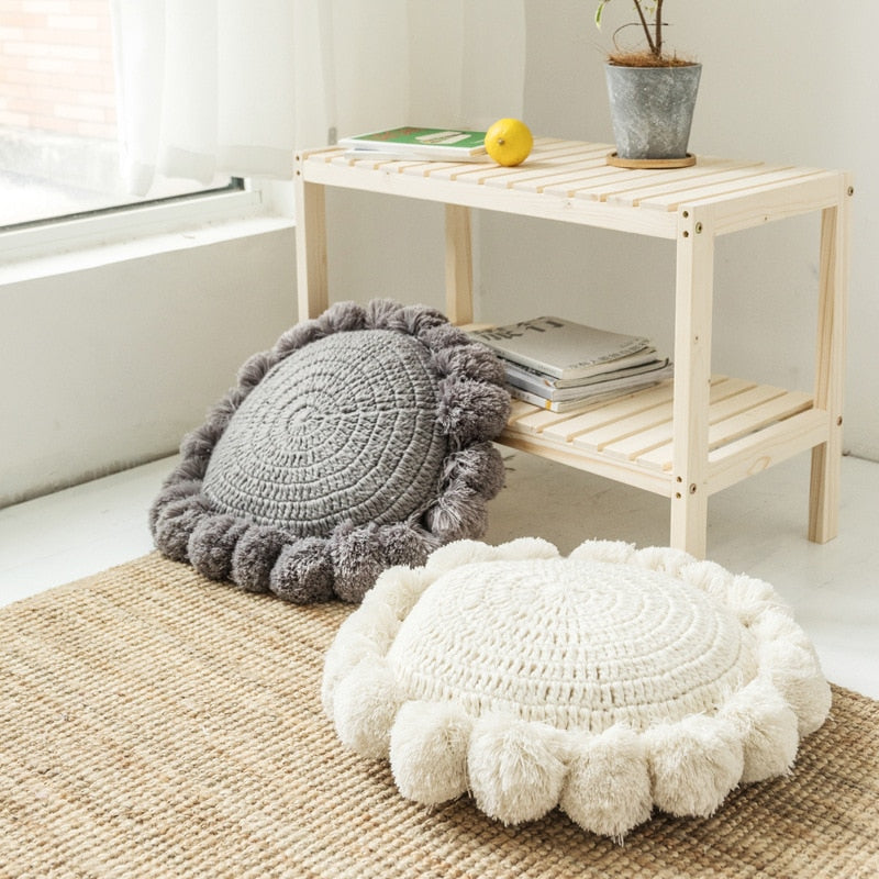 VibeCore Hand-Knitted Pompom Cushions in white and gray on the floor, highlighting their boho design and soft, plush texture as floor pillows.