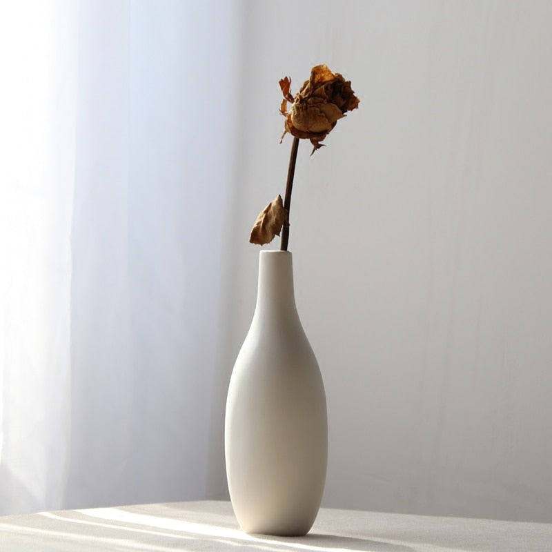 VibeCore Matte White Ceramic Flower Vase with fake flowers on table, showcasing a minimalist tube design, perfect for adding a modern touch and enhancing any room decor with faux floral arrangements.