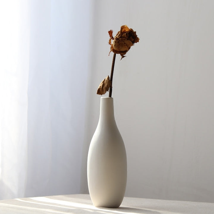 VibeCore Matte White Ceramic Flower Vase with fake flowers on table, showcasing a minimalist tube design, perfect for adding a modern touch and enhancing any room decor with faux floral arrangements.