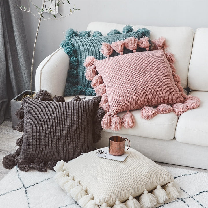 VibeCore Nordic Style Hand-Knitted Pillow Cover, 4 colors (blossom, ivory, dark gray, turquoise blue) displayed in a cozy living room with fringe details for a boho-inspired look.