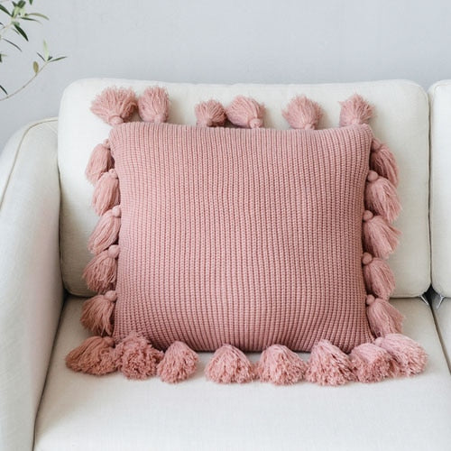 VibeCore Nordic Style Hand-Knitted Pillow Cover in Blossom color, featuring fringe details for a cozy, boho-inspired touch, placed on a couch or chair.
