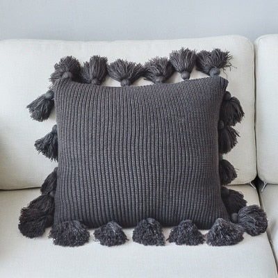 VibeCore Nordic Style Hand-Knitted Pillow Cover in Dark Gray, showcasing fringe details and a cozy, boho-inspired design, displayed on a couch or chair.