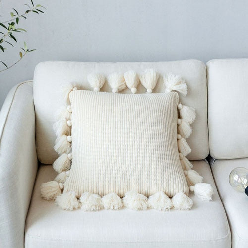 VibeCore Nordic Style Hand-Knitted Pillow Cover in Ivory, featuring fringe details and a boho design, placed on a cozy chair or couch.
