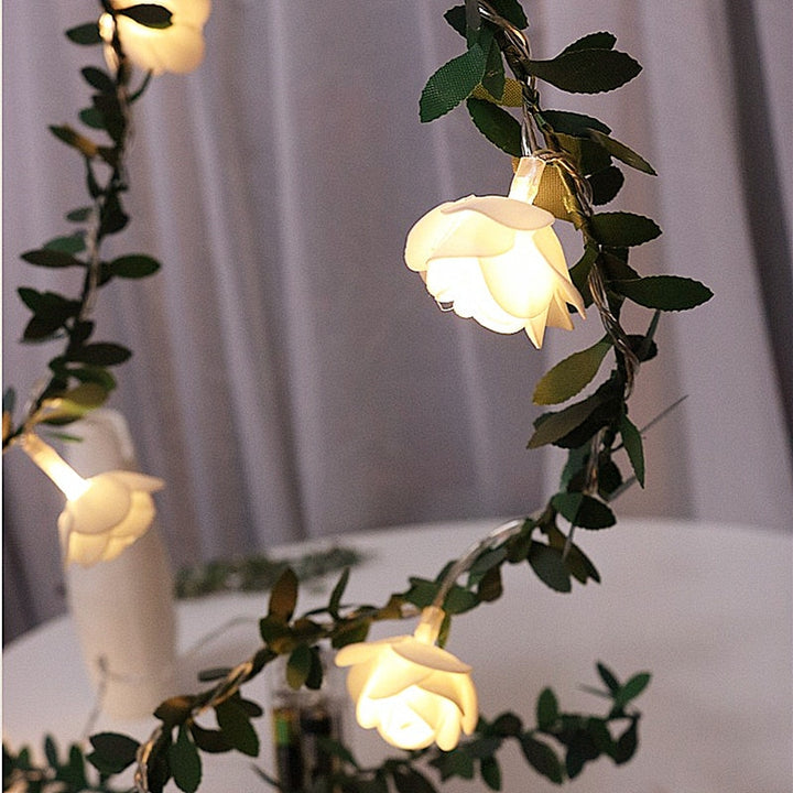 Close-up of VibeCore rose flower string lights lit up, glowing with a soft, warm white light that creates a cozy, inviting ambiance.