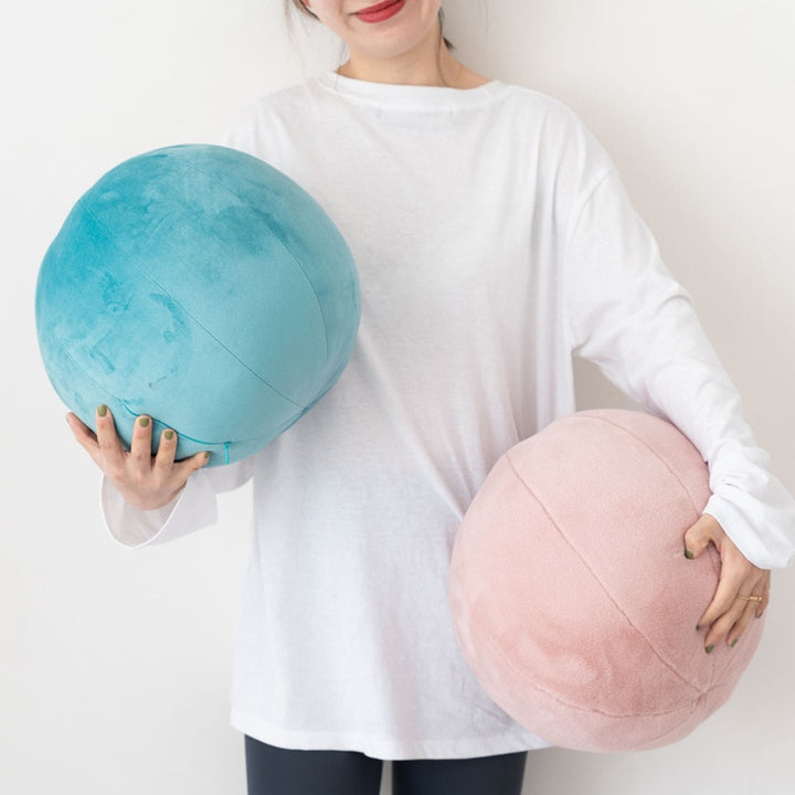 VibeCore Velvet Ball Pillows in mauve and yellow, girl holding two plush round velvet pillows, cozy and stylish decor for modern bedroom or lounge space.