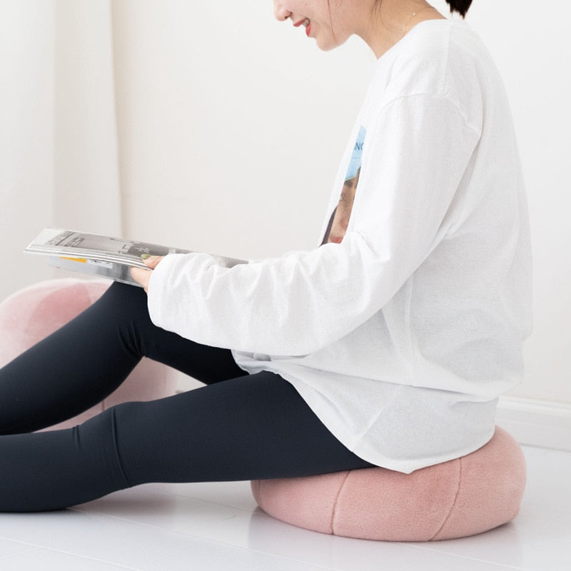 VibeCore Velvet Ball Pillow in mauve, girl sitting on plush round velvet pillow, adding a stylish and cozy accent to bedroom or living room decor.