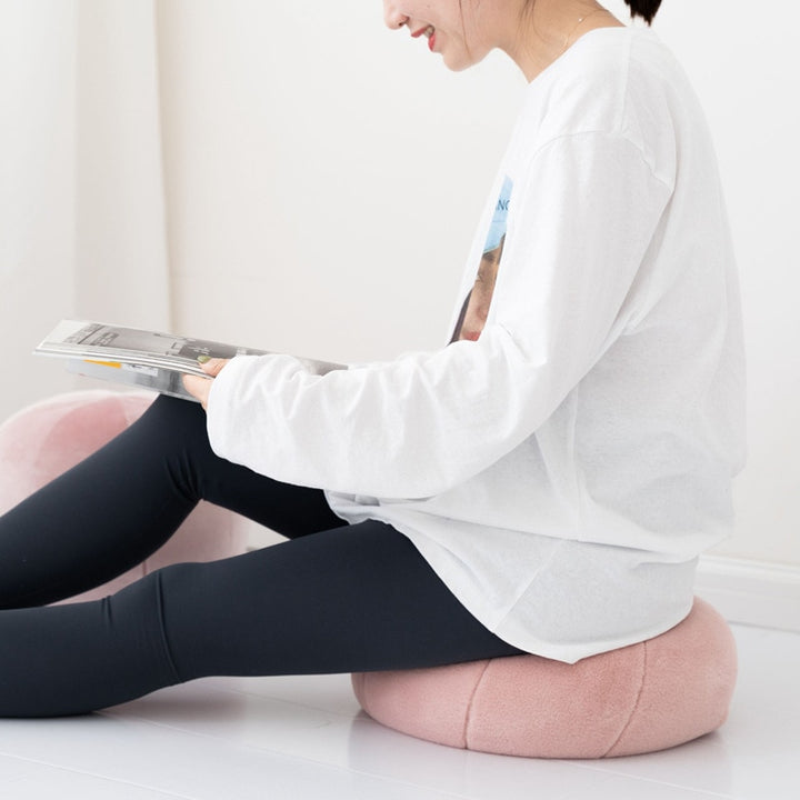 VibeCore Velvet Ball Pillow in mauve, girl sitting on plush round velvet pillow, adding a stylish and cozy accent to bedroom or living room decor.